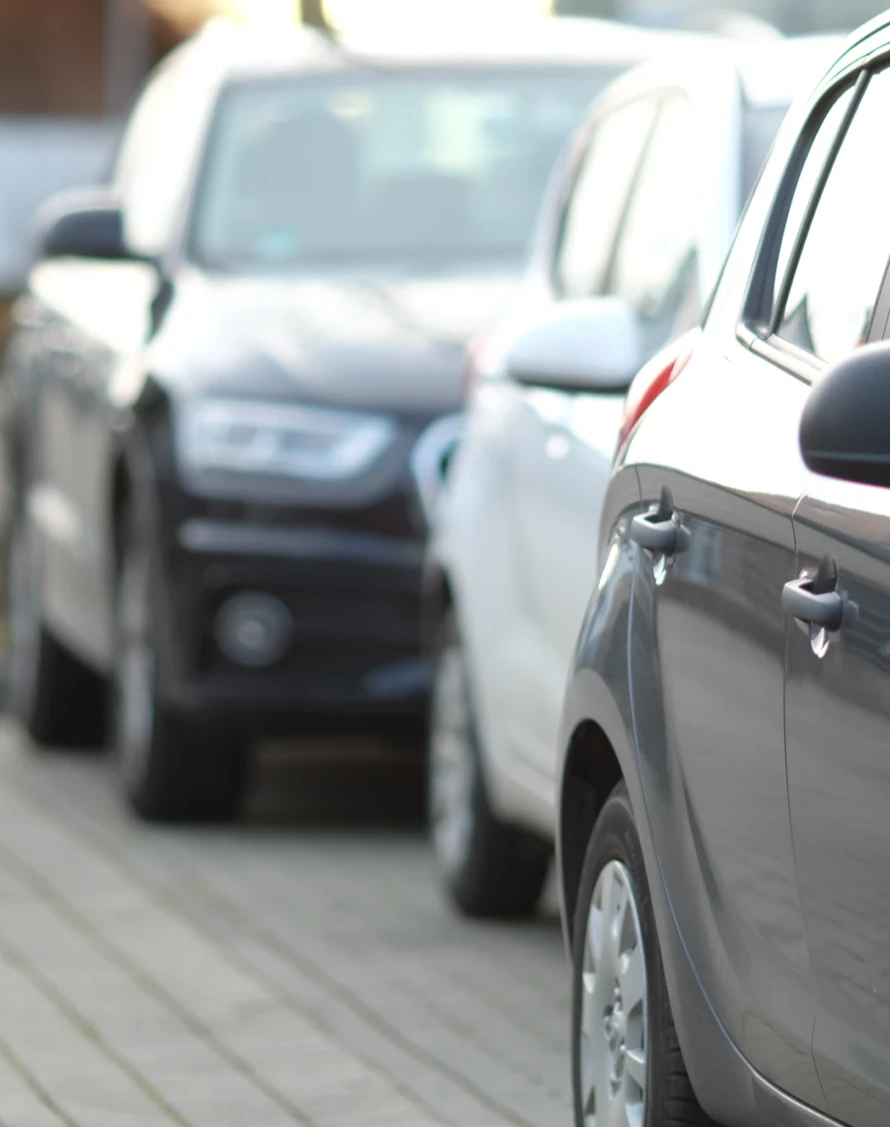 Cars parked in a row on the brick lot outside the hotel